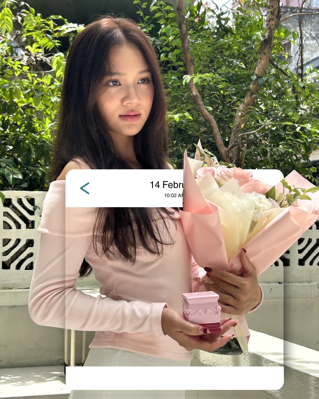 A woman in a pink top holding a bouquet and a small pink gift box outdoors, inside a phone-style '14 February' message card (slide 1 of 4)