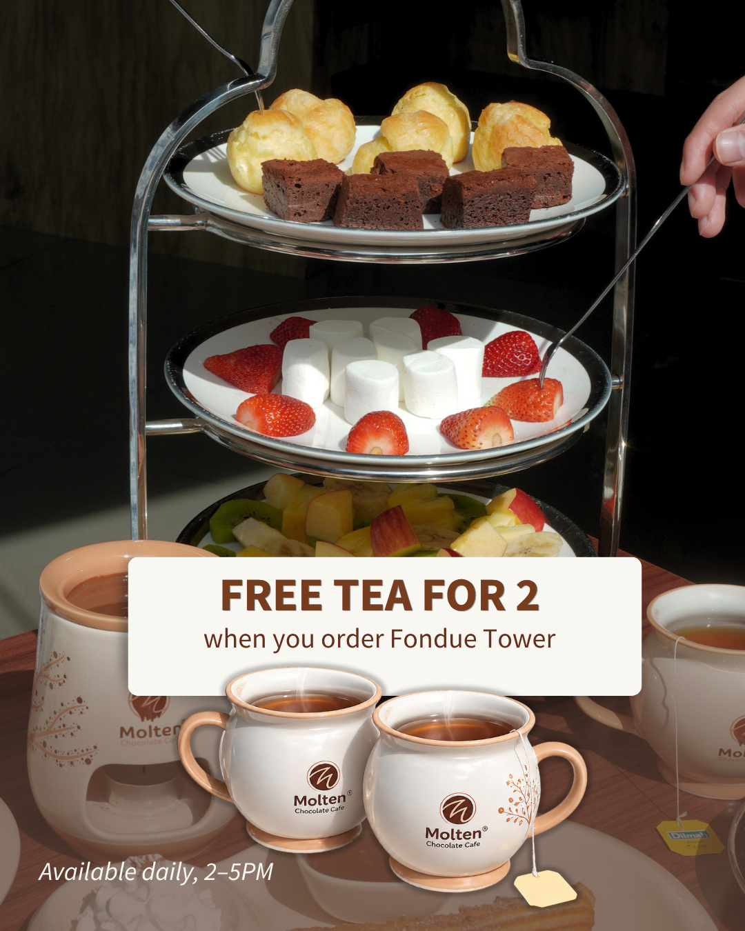 A tiered fondue tower of brownies, cream puffs, strawberries, marshmallows and fruit with two cups of tea, with the text 'Free tea for 2 when you order Fondue Tower' (slide 1 of 3)